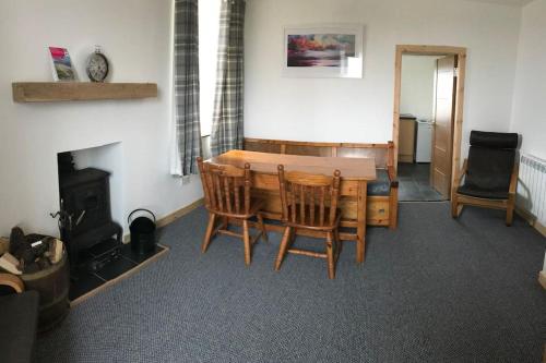 a dining room with a table and chairs and a fireplace at Traditional Croft house in Creagorry