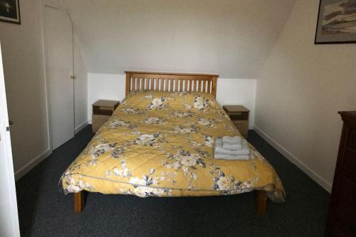 a bed with a yellow comforter with towels on it at Traditional Croft house in Creagorry