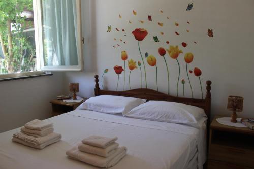 1 dormitorio con 1 cama con flores en la pared en Mille Bouganville, en Platamona