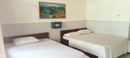 two beds in a room with a painting on the wall at NEW CORALs in Gili Trawangan