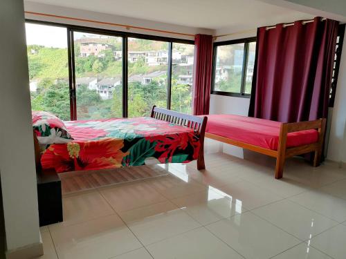 a bedroom with a bed and a large window at Manapiti on the hill in Papeete