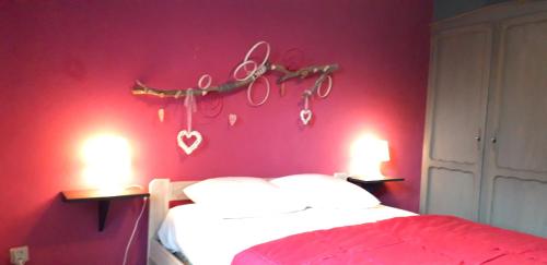 a bedroom with a red wall with a bed and two lights at L'orée du bois in Roy