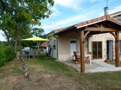 um pátio com uma mesa e um guarda-chuva em Lumineuse maison de vacances avec jardin clos em Bussière-Boffy