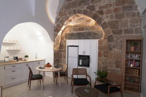 a kitchen with a table and chairs and a stone wall at Beit-sitti in Acre