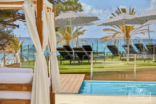 einen Pool mit Stühlen und Sonnenschirmen neben einem Resort in der Unterkunft Secrets Mallorca Villamil Resort & Spa - Adults Only (+18) in Paguera