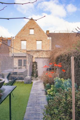 a garden with a brick house with a garage at Vakantiehuis Juliette in Diksmuide