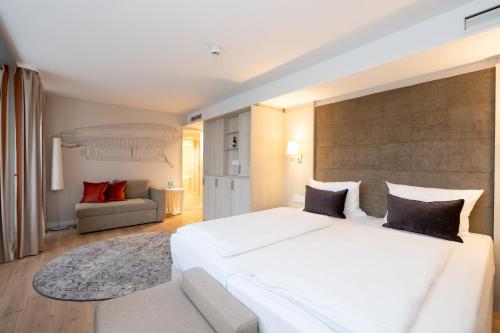 a bedroom with a large white bed and a couch at Kongresshotel Potsdam am Templiner See in Potsdam