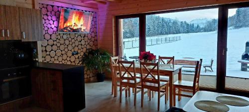 a dining room with a table and chairs and a fireplace at Sołtysie Chaty - Domek z prywatną balią in Łapsze Niżne