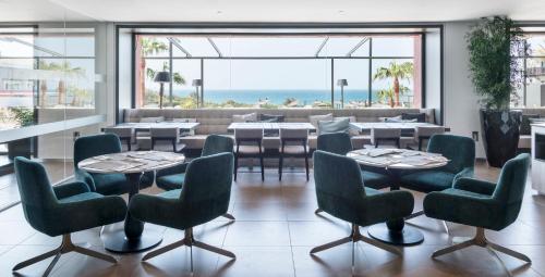 a restaurant with tables and chairs and a view of the ocean at Ilunion Calas de Conil in Conil de la Frontera