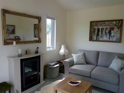 sala de estar con sofá y chimenea en Coastal Garden Lodge, en Preesall