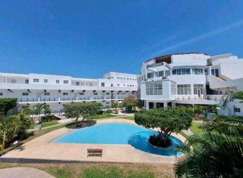- un grand bâtiment blanc avec une piscine en face dans l'établissement Loft 202, à Acapulco