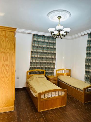 a bedroom with two beds and a chandelier at شقق الياسمين 2 in Jerash
