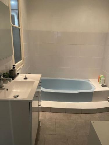 La salle de bains est pourvue d'une baignoire bleue et d'un lavabo. dans l'établissement CÔTE D’AZUR Appart spacieux / lumineux, à Toulon