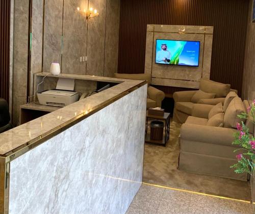 vestíbulo con zona de espera con TV y sillas en وردة رومه للوحدات السكنية en Medina