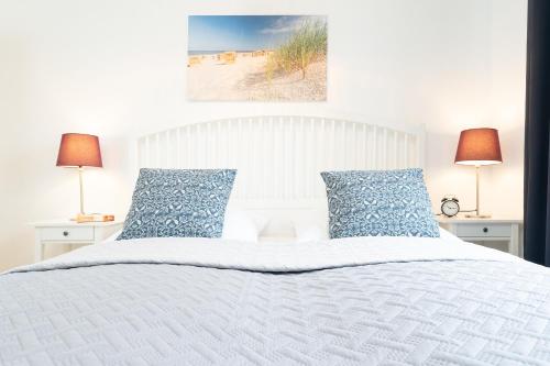 een slaapkamer met een wit bed met blauwe kussens bij Seestraße 43 Wohnung 1 in Scharbeutz