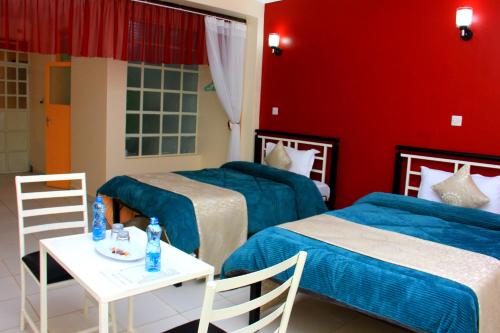 a hotel room with two beds and a table with a table at Eland Accommodations - Ongata Rongai in Ongata Rongai 