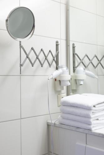 a bathroom with a mirror and a pile of towels at Hotel Reichskrone in Heidenau