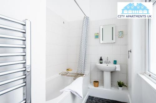 Baño blanco con lavabo y bañera en Charming 1 Bed Apt in Kensington - Free London Tour Included By City Apartments UK Short Lets Serviced Accommodation, en Londres