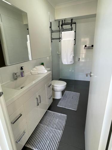 a bathroom with a sink and a toilet and a mirror at Private guesthouse - Minutes from the beach! in Mornington