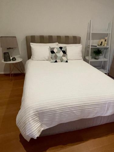 a white bed with a black and white pillow on it at Private guesthouse - Minutes from the beach! in Mornington