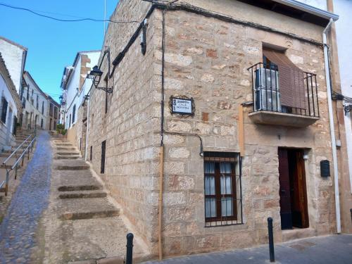 un antico edificio in pietra con scala e balcone di La Casa del Abuelo Curro a Baños de la Encina