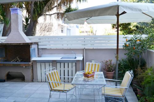 un patio con mesa, sillas y sombrilla en Kalamata beach maizonette ground floor and semi-basement with yard, en Kalamata