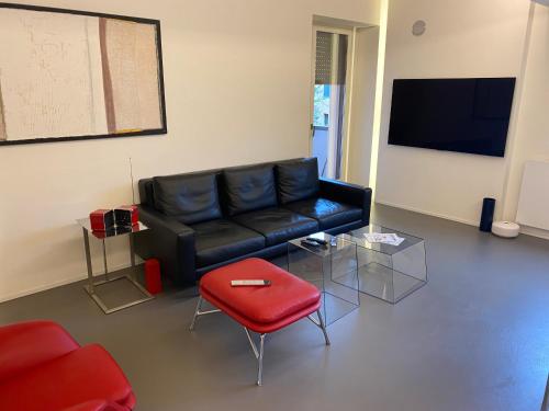 a living room with a black leather couch and a red stool at Cortirola luxury apartment in Pesaro