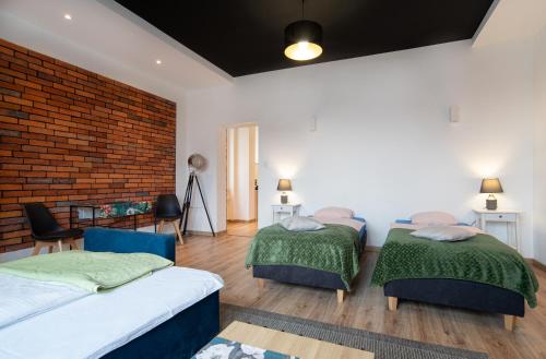 a bedroom with two beds and a brick wall at Apartamenty Weneckie in Zielona Góra