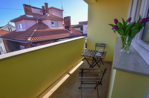 a balcony with a table and chairs and a vase of flowers at Apartment Gate Old Town in Zadar