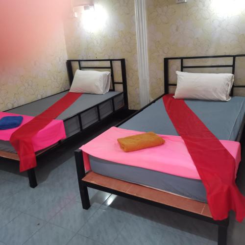 two beds in a room with red and pink sheets at Haadrin Village near the pier in Haad Rin