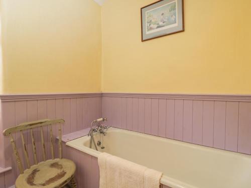 ein Badezimmer mit einer Badewanne und einem Stuhl in der Unterkunft Field Cottage in Shepton Mallet