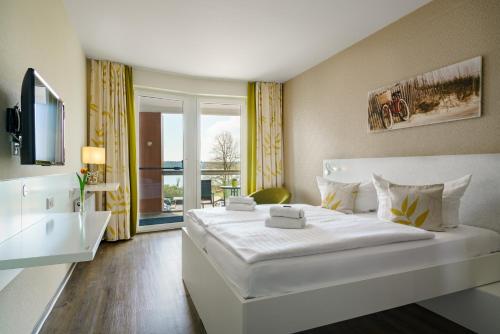 ein Hotelzimmer mit einem großen weißen Bett und einem Fenster in der Unterkunft Radlon Fahrrad-Komfort-Hotel in Waren (Müritz)