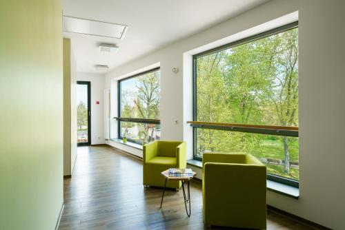 a living room with two chairs and large windows at Radlon Fahrrad-Komfort-Hotel in Waren
