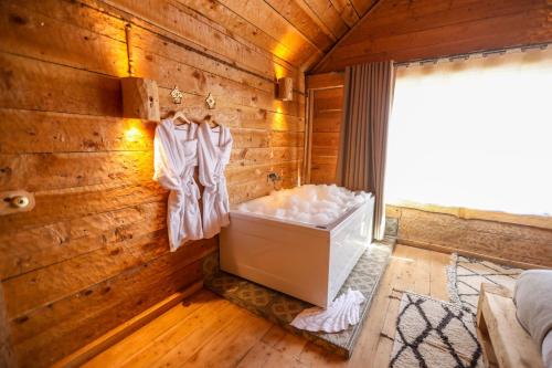 a bedroom with a wooden wall with a bath tub at Hotel Xaluca Spa Aguelmame Sidi Ali in Aguelman