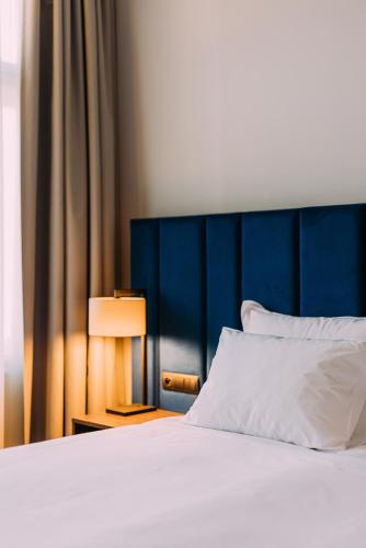 a bed with a blue headboard and a white pillow at Grandhotel Pupp in Karlovy Vary