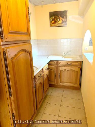 Elle comprend une petite cuisine avec des placards en bois et un évier. dans l'établissement Appartement charmant à Lacrost avec jardin privé - 60 m², à Lacrost