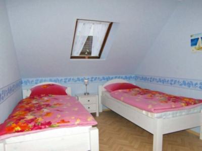- une chambre avec 2 lits et un miroir dans l'établissement Kapitänshaus, à Neuharlingersiel