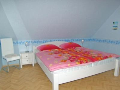 - une chambre avec un lit blanc et une chaise dans l'établissement Kapitänshaus, à Neuharlingersiel