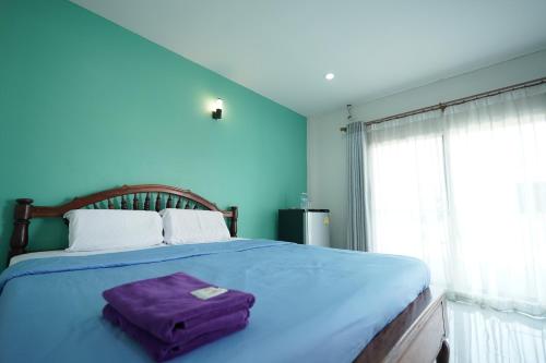 Un dormitorio azul con una cama grande con una bolsa morada. en Baan Sabuy Jung en Aranyaprathet