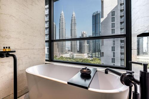 La salle de bains est pourvue d'une baignoire et d'une grande fenêtre. dans l'établissement The RuMa Hotel and Residences, à Kuala Lumpur