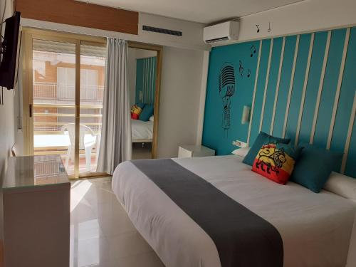 1 dormitorio con 1 cama grande y paredes azules en Hotel Clibomar Jamaica, en Gandía