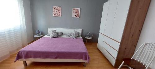 ein Schlafzimmer mit einem Bett mit einer lila Decke in der Unterkunft Apartman Alenka in Tkon