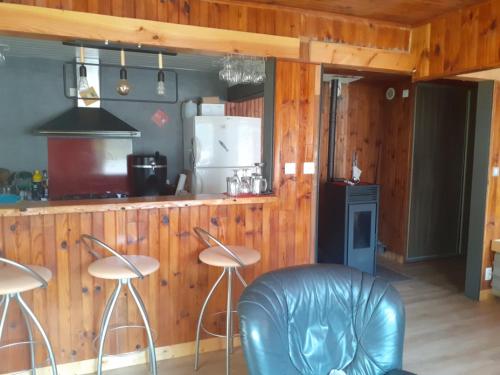 a kitchen with two stools and a counter with a refrigerator at la maison blanche in Ustou