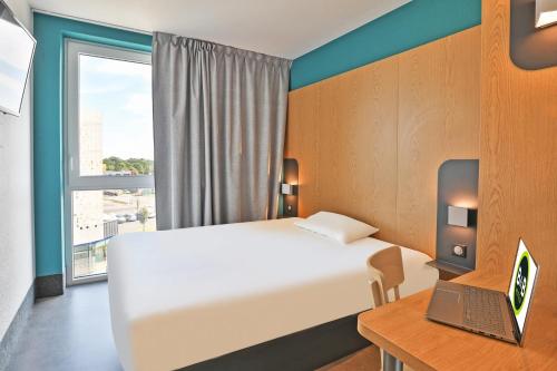 1 dormitorio con cama y escritorio con ordenador portátil en B&B HOTEL La Roche-sur-Yon en Mouilleron-le-Captif