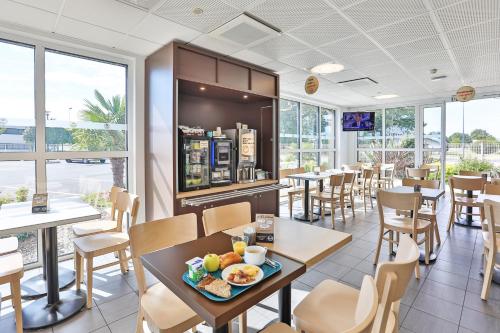 un restaurant avec des tables, des chaises et des fenêtres dans l'établissement B&B HOTEL La Roche-sur-Yon, à Mouilleron-le-Captif