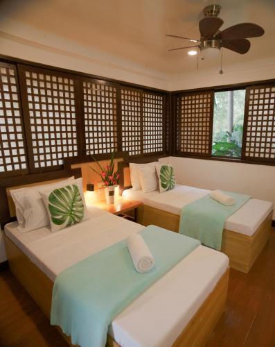 a bedroom with two beds and a ceiling fan at Aquaventure Reef Club in Mabini