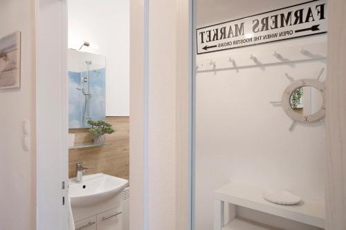 een witte badkamer met een wastafel en een spiegel bij Weidenweg 25 Weidennest in Grömitz