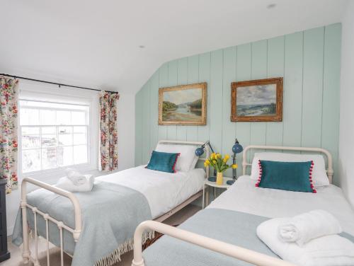 two twin beds in a room with a window at Seagull Cottage in Beaumaris