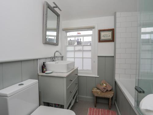 ein Bad mit einem Waschbecken, einem WC und einem Fenster in der Unterkunft Seagull Cottage in Beaumaris