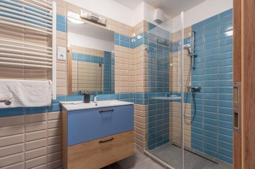 a bathroom with a sink and a shower with blue tiles at Casa Iringo Apartman By BLTN Balatonföldvár in Balatonföldvár